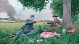 | `Fromage.jpg` | Deux soldats WWII en reconstitution partagent du fromage dans un champ (film Cr&egrave;me) | `Extrait de film publicitaire Cr&egrave;me pour La Normandie : deux soldats en reconstitution WWII partagent du fromage normand en plein champ` |